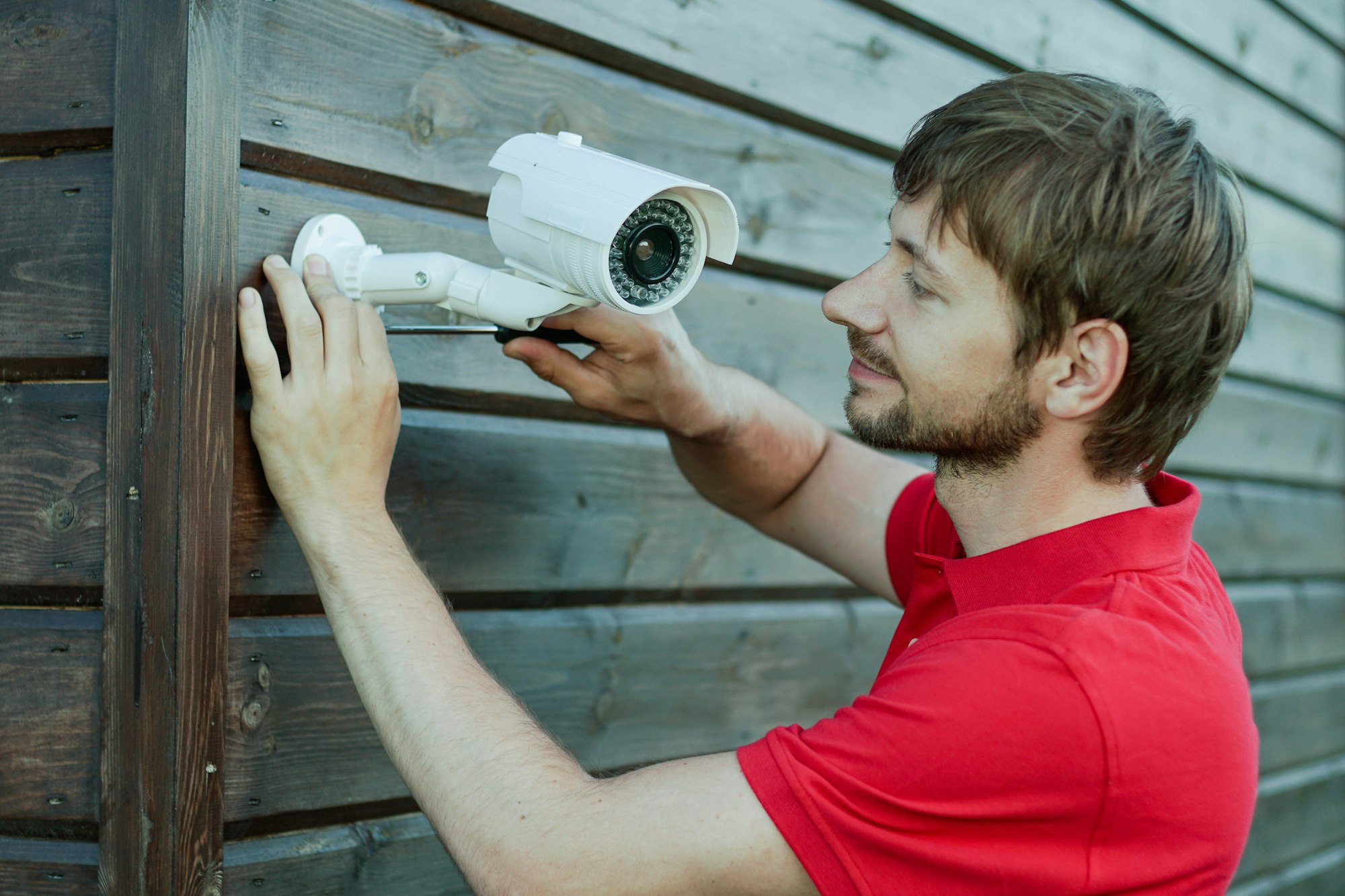 Técnico caucásico instalando una cámara CCTV inalámbrica IP atornillada para el sistema de seguridad del hogar